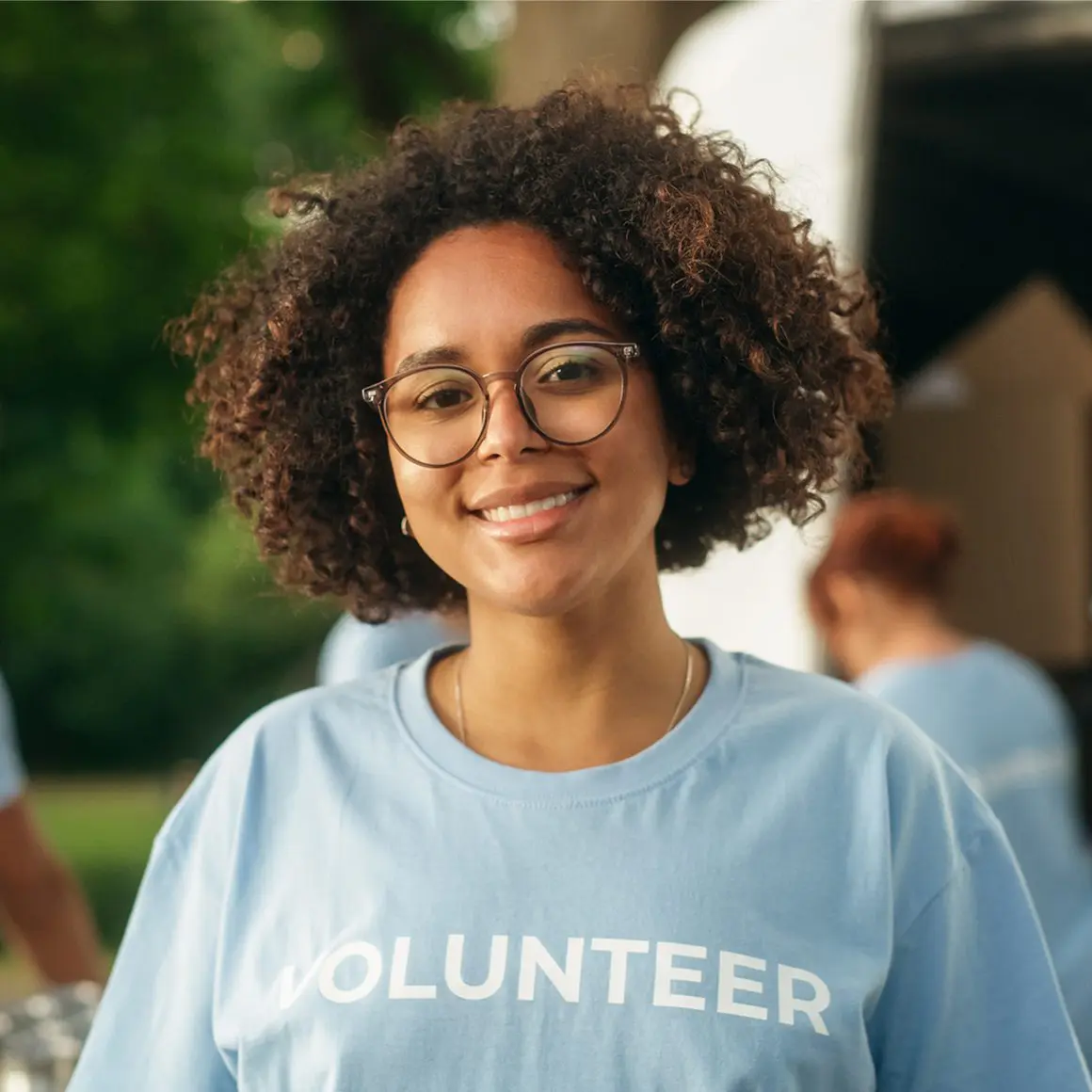 Volunteer smiling outdoors in a blue shirt.