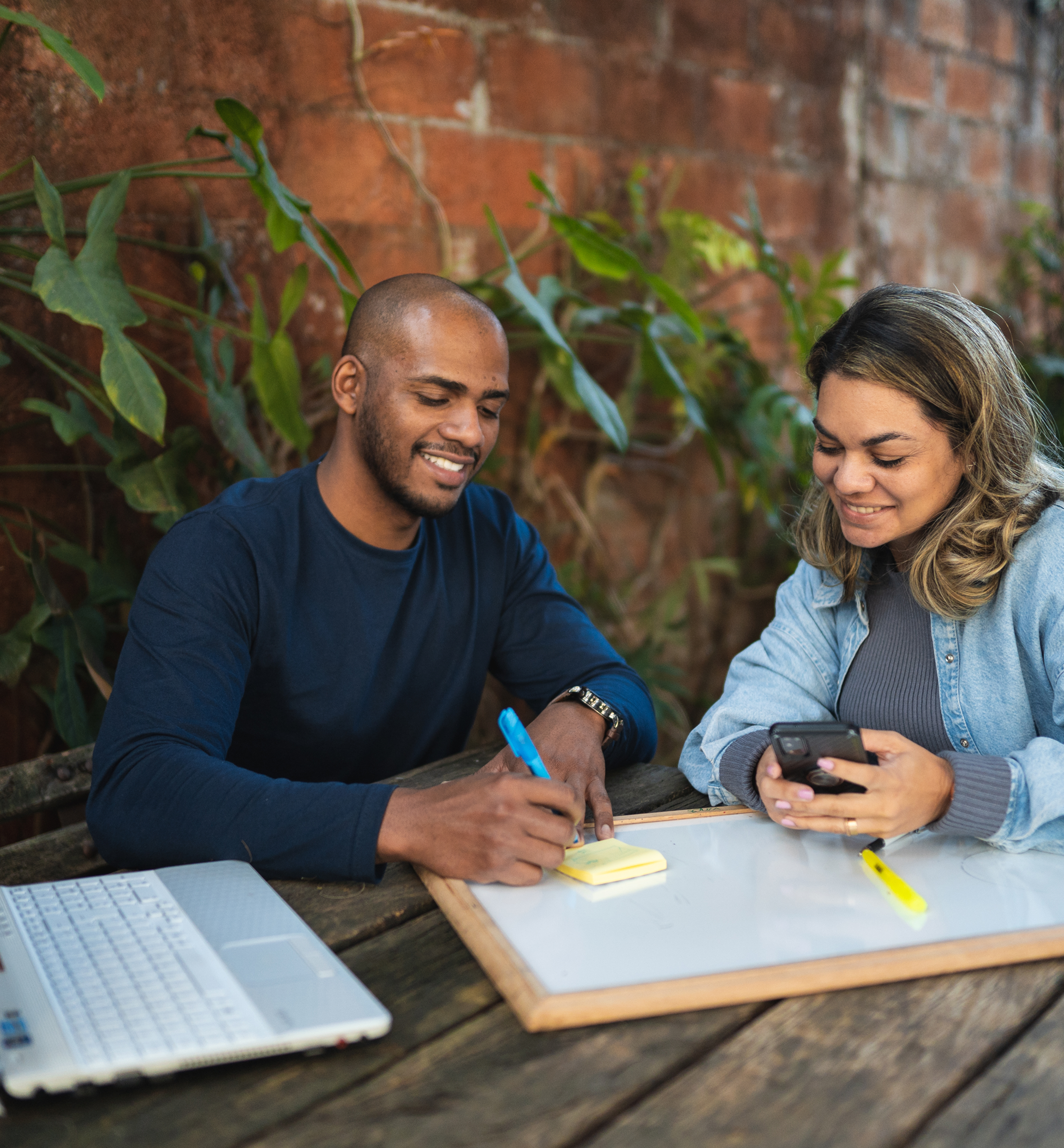 Two people collaborating outdoors with technology.