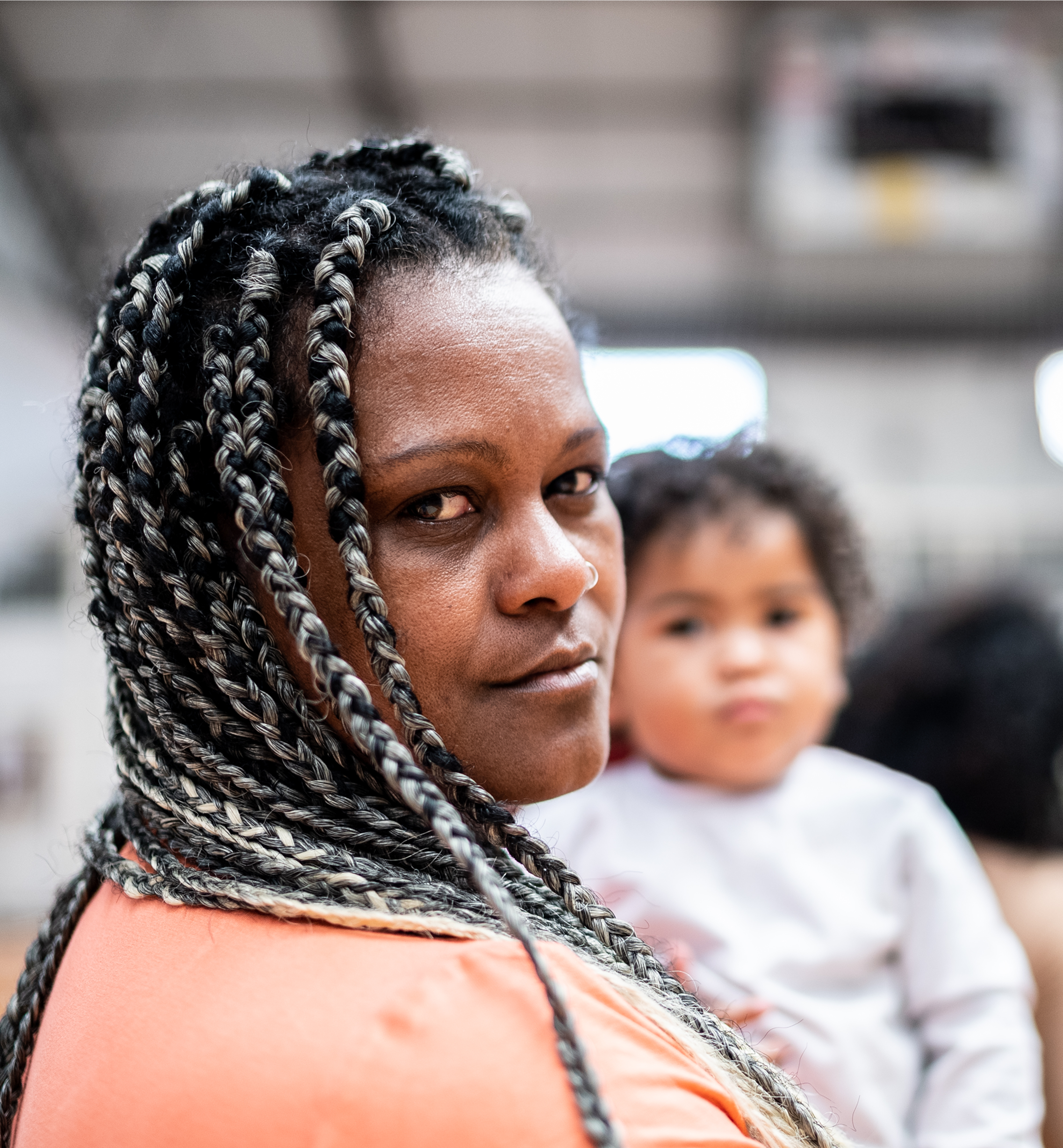 Mother holding baby, looking at camera.