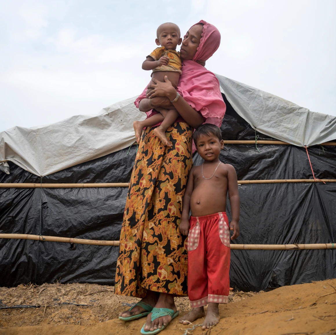 Woman with two children near temporary shelter.