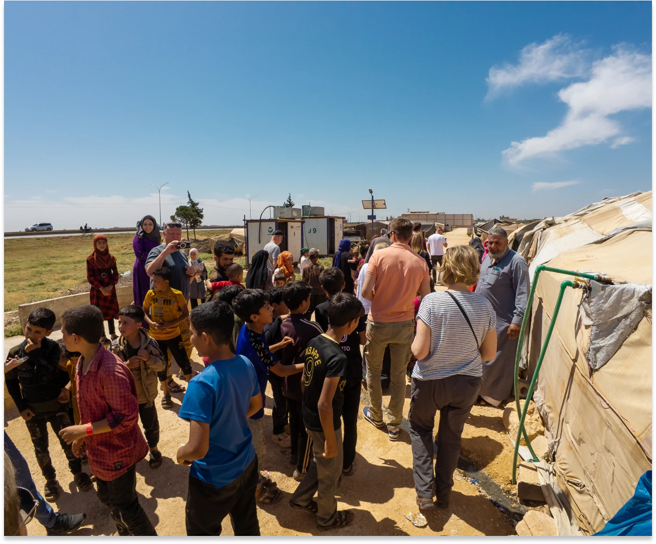 People gathered near tents under clear sky.